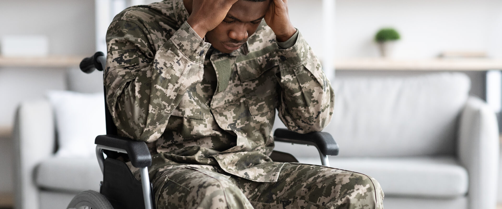 Upset black man sitting in wheelchair, wearing military uniform